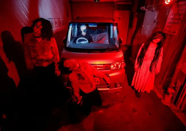 Actors dressed as zombies or ghouls perform during a drive-in haunted house show by Kowagarasetai (Scare Squad), for people inside a car in order to maintain social distancing amid the spread of the coronavirus disease (COVID-19), at a garage in Tokyo, Japan on July 3, 2020. (Photo by Issei Kato/Reuters)