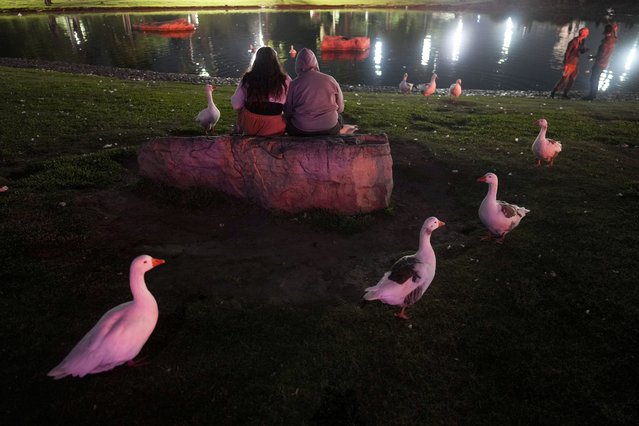 People sit outside the planetarium to watch the total lunar eclipse in Buenos Aires, Argentina, Friday, March 14, 2025. (Photo by Natacha Pisarenko/AP Photo)