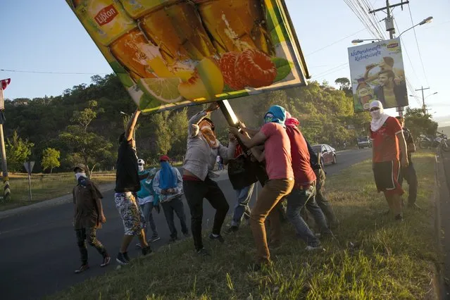 Supporters of presidential candidate Salvador Nasralla pull down a sign to add to a roadblock as they protest what they call electoral fraud in Tegucigalpa, Honduras, Friday, December 1, 2017. (Photo by Rodrigo Abd/AP Photo)