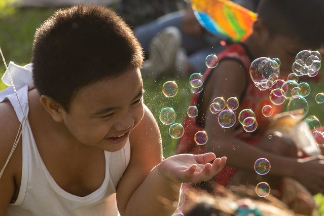 A child plays with bubbles as people gather at Rizal Park on Christmas day in Manila on December 25, 2023. (Photo by Earvin Perias/AFP Photo)