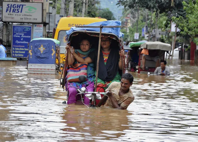 People use cycle rickshaws to commute through a flooded road after heavy rains in Guwahati September 23, 2014. (Photo by Utpal Baruah/Reuters)