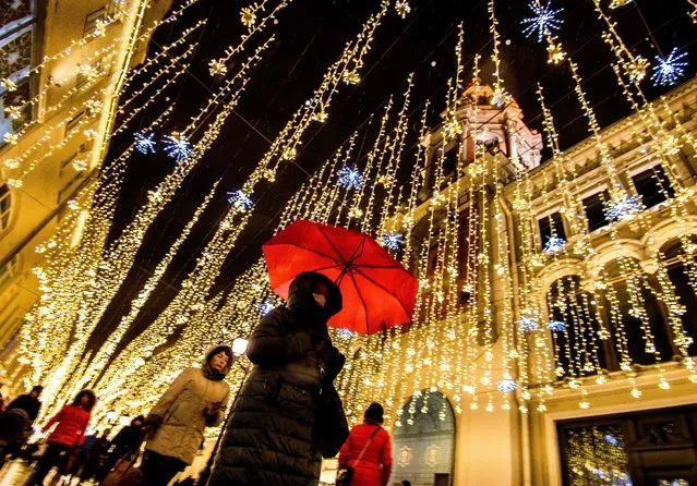 A woman protects herself from the snow with an umbrella as she walks under the Christmas decorations set on a street in central Moscow on December 18, 2017. (Photo by Mladen Antonov/AFP Photo)