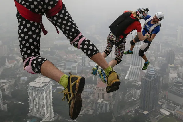 BASE jumpers are pictured against the skyline shrouded in a thick haze during the Kuala Lumpur Tower International Jump in Kuala Lumpur, Malaysia, 02 October 2015. (Photo by Fazry Ismail/EPA)
