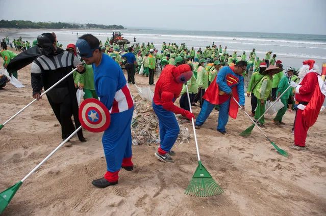 Workers wearing super hero costumes to attract tourists, sweep up garbage at Kuta Beach, Bali, Indonesia December 27, 2017 in this photo taken by Antara Foto. (Photo by Nyoman Budhiana/Reuters/Antara Foto)