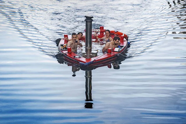 A group of people sit inside a hot tub boat sailing on the River Thames at Canary Wharf in London, Tuesday August 18, 2020. (Photo by Victoria Jones/PA Wire Press Association via AP Photo)