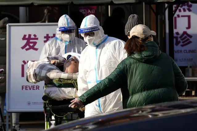 An elderly man on a stretcher is wheeled from the fever clinic at a hospital in Beijing, Friday, December 9, 2022. China began implementing a more relaxed version of its strict “zero COVID” policy on Thursday amid steps to restore normal life, but also trepidation over a possible broader outbreak once controls are eased. (Photo by Ng Han Guan/AP Photo)