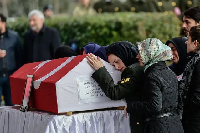 The wife of Fatih Mehmethan, a Turkish soldier killed in cross-border clashes with Kurdish People's Protection Units (YPG) forces in Afrin, reacts over his Turkish flag-draped coffin during a funeral ceremony at 15 Temmuz Sehitler Mosque in Istanbul on January 28, 2018. Turkey launched operation “Olive Branch” on January 20 against the Syrian Kurdish People's Protection Units (YPG) in Afrin, supporting Syrian opposition fighters with ground troops and air strikes. (Photo by Yasin Akgul/AFP Photo)