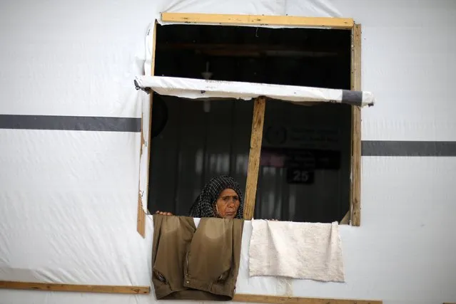 A Palestinian woman, who lives in a container as a temporary replacement for her house that witnesses said was destroyed by Israeli shelling during the most recent conflict between Israel and Hamas, looks out on a rainy day in the east of Khan Younis in the southern Gaza Strip November 16, 2014. (Photo by Ibraheem Abu Mustafa/Reuters)
