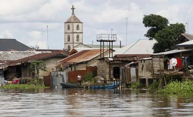 A church minaret is seen behind houses built near the banks of the Nun River on the outskirts of the Bayelsa state capital, Yenagoa, in Nigeria's delta region October 8, 2015. (Photo by Akintunde Akinleye/Reuters)
