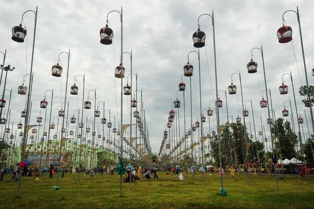Birds sit in their cages, hoisted on poles during a bird-singing contest in Thailand's southern province of Narathiwat on September 20, 2016. Over one thousand birds from Thailand, Malaysia and Singapore take part in the annual contest. (Photo by Madaree Tohlala/AFP Photo)