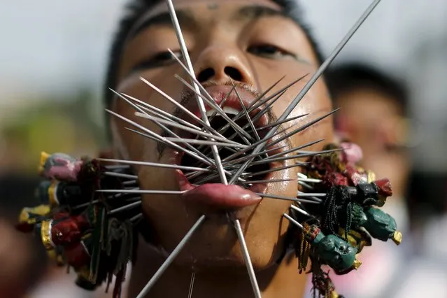 A devotee of the Chinese Samkong Shrine walks with spikes pierced through his cheeks during a procession celebrating the annual vegetarian festival in Phuket, Thailand, October 16, 2015. (Photo by Jorge Silva/Reuters)
