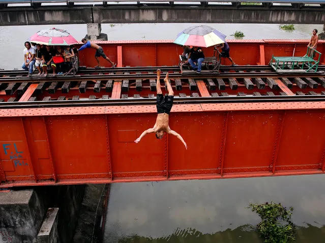 Filipinos ride rickshaws on rails as a person jumps into the water from a train track bridge in Manila, Philippines, 22 September 2017. According to media reports, the National Economic and Development Authority (NEDA) Board approved the Metro Manila Subway Project (MMSP) to improve the worsening mass transport service in Metro Manila. (Photo by Francis R. Malasig/EPA/EFE)