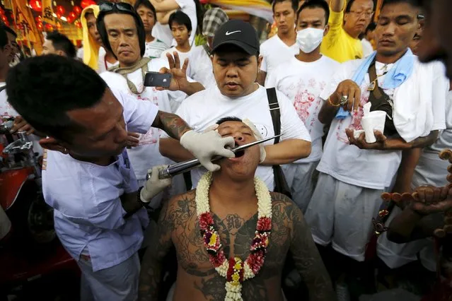A devotee of the Chinese Bang Neow shrine has his cheeks pierced before a procession celebrating the annual vegetarian festival in Phuket, Thailand October 18, 2015. (Photo by Jorge Silva/Reuters)