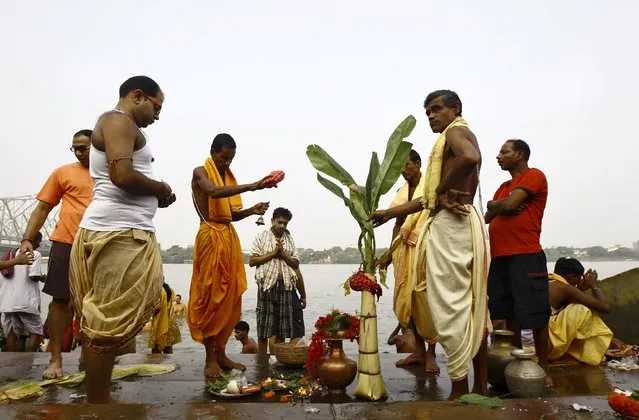 Hindu priests perform prayers in front of a banana tree trunk as part of a ritual on the banks of the Ganges river during Durga Puja festival in Kolkata, India, October 20, 2015. (Photo by Rupak De Chowdhuri/Reuters)