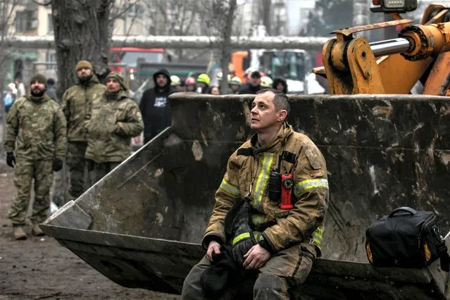 An emergency worker rests at the site where an apartment block was heavily damaged by a Russian missile strike, amid Russia's attack on Ukraine, in Dnipro, Ukraine on January 15, 2023. (Photo by Yevhenii Zavhorodnii/Reuters)
