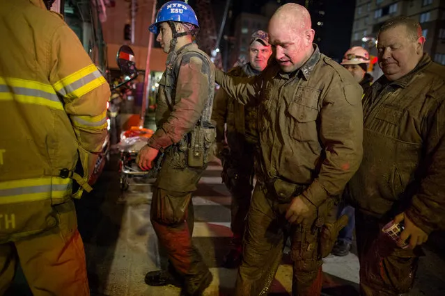 Officers of the New York City police Emergency Services Unit, covered in mud and dirt, walk to a waiting bus to warm up after securing the rescue of a construction worker trapped underground at an MTA subway construction project in New York early Wednesday, March 20, 2013. The worker, trapped for several hours, was lifted from underground with the assistance of the New York police and fire departments. Fire officials say he is awake and conscious and is being evaluated at a local hospital. (Photo by Craig Ruttle/AP Photo)