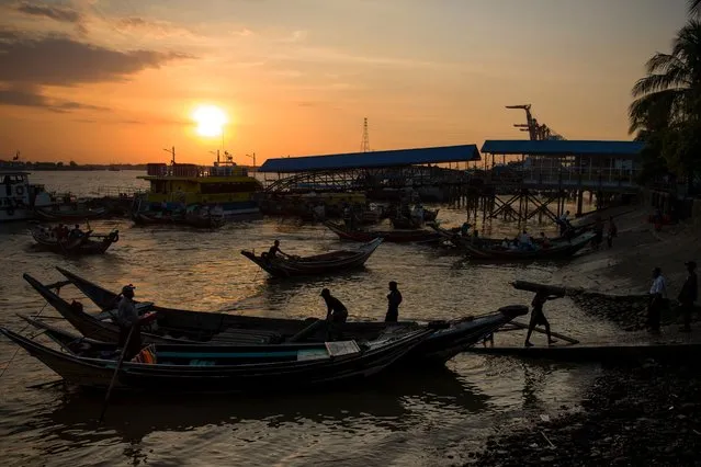 This photo taken on December 1, 2017 shows a labourer (bottom R) unloading goods from a boat during sunset at the Yangon jetty. (Photo by Ye Aung Thu/AFP Photo)