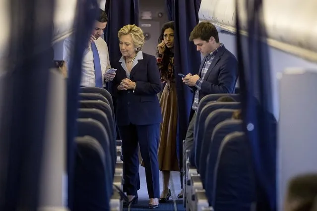 Democratic presidential candidate Hillary Clinton, accompanied by senior aid Huma Abedin, second from right, and traveling press secretary Nick Merrill, right, speaks with national press secretary Brian Fallon, left, aboard her campaign plane in White Plains, N.Y., Monday, October 3, 2016, before traveling to Toledo, Ohio. (Photo by Andrew Harnik/AP Photo)