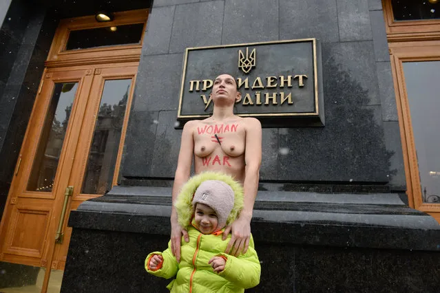 A FEMEN topless feminist activist protests with her daughter outside Ukraine's President office in Kyiv on January 27, 2022 against the government project of military registration for women. (Photo by femen.org)