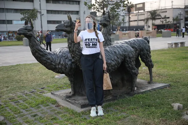 A woman, wearing a T-shirt with a message that reads in Spanish: “This Congress does not represent me”, takes a selfies leaning on the llamas statue outside the Justice Palace where people who are refusing to recognize the new government gathered to protest, in Lima, Peru, Wednesday, November 11, 2020. (Photo by Rodrigo Abd/AP Photo)