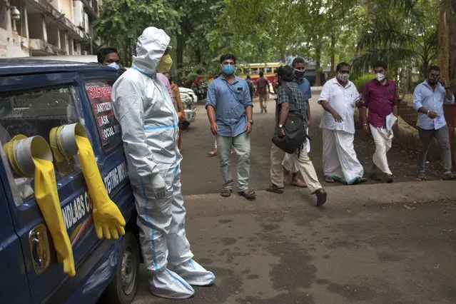 A man in protective suit stands next to a mobile COVID-19 testing kiosk outside the Ernakulam district administration headquarters in Kochi, Kerala state, India, Wednesday, November 18, 2020. A country of nearly 1.4 billion people, India is the world's second most coronavirus affected country after the United States. (Photo by R.S. Iyer/AP Photo)