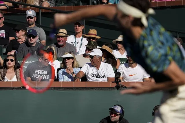 A man, at left, wears a shirt that says “free Novak”, in the crowd as Taylor Fritz, right, serves to Jannik Sinner, of Italy, at the BNP Paribas Open tennis tournament Thursday, March 16, 2023, in Indian Wells, Calif. (Photo by Mark J. Terrill/AP Photo)