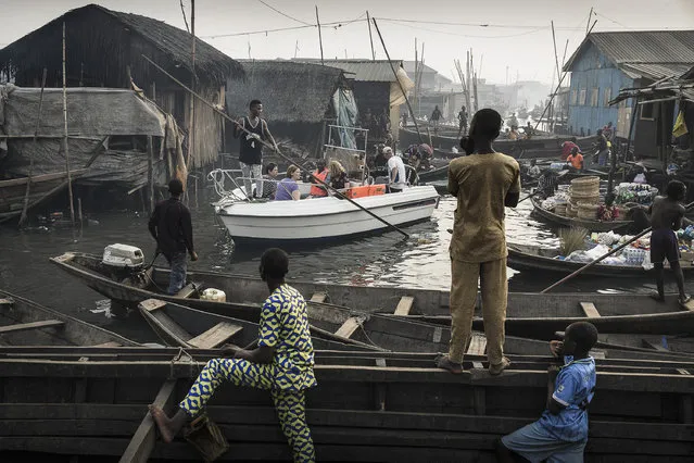 Lagos Waterfronts under Threat: A boat with expats from Lagos Marina is steered through the canals of Makoko community – an ancient fishing village that has grown into an enormous informal settlement – on the shores of Lagos Lagoon, Lagos, Nigeria, February 24, 2017. Makoko has a population of around 150,000 people, many of whose families have been there for generations. But Lagos is growing rapidly, and ground to build on is in high demand. Prime real estate along the lagoon waterfront is scarce, and there are moves to demolish communities such as Makoko and build apartment blocks: accommodation for the wealthy. Because the government considers the communities to be informal settlements, people may be evicted without provision of more housing. Displacement from the waterfront also deprives them of their livelihoods. The government denies that the settlements have been inhabited for generations and has given various reasons for evictions, including saying that the communities are hideouts for criminals. Court rulings against the government in 2017 declared the evictions unconstitutional and that residents should be compensated and rehoused, but the issue remains unresolved. (Photo by Jesco Denzel/World Press Photo)