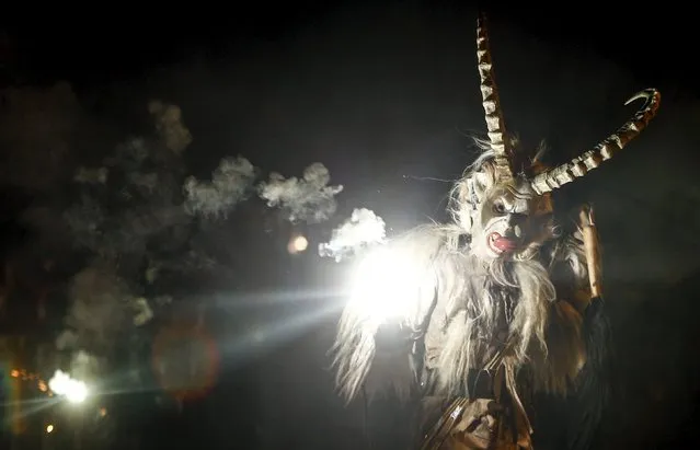 A man dressed in a traditional Perchten costume and mask performs during a Perchten festival in the western Austrian village of Kappl, November 13, 2015. Each year in November and January, people in the western Austria regions dress up in Perchten (also known in some regions as Krampus or Tuifl) costumes and parade through the streets to perform a 1,500 year-old pagan ritual to disperse the ghosts of winter. (Photo by Dominic Ebenbichler/Reuters)