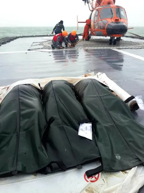 A Basarnas helicopter is seen behind three covered bodies recovered from the AirAsia plane, on the deck of KRI Bung Tomo warship off the Java Sea, Indonesia, December 31, 2014 in this photo taken by Antara Foto. A body recovered on Wednesday from the crashed AirAsia plane was wearing a life jacket, an official with Indonesia's search and rescue agency said, raising questions about how the disaster unfolded. (Photo by Lettu Solihin/Reuters/Antara Foto)