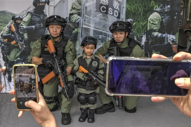 A child with members of the Hong Kong Correctional Services Department poses for a photo at the Hong Kong Correctional Services Academy Open Day during the National Security Education Day in Hong Kong, Saturday, April 15, 2023. (Photo by Louise Delmotte/AP Photo)
