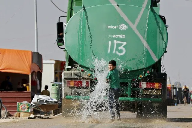 A Syrian refugee child plays in the water from the back of a water tanker at Al Zaatari refugee camp, in the Jordanian city of Mafraq, near the border with Syria, November 29, 2015. (Photo by Muhammad Hamed/Reuters)