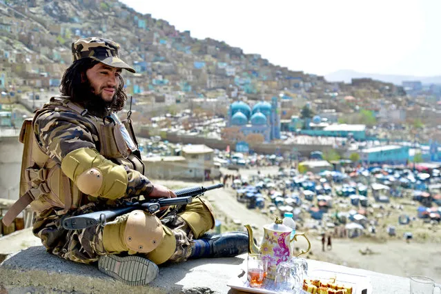 A Taliban fighter sits against the backdrop of Karte Sakhi shrine on the first day of “Nowruz” marking the Persian New Year in Kabul on March 21, 2022. (Photo by Ahmad Sahel Arman/AFP Photo)