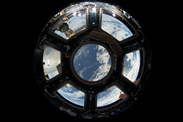 A view of Earth from the Cupola on the earth-facing side of the International Space Station is seen in this NASA handout photo taken June 12, 2103 and provided June 17, 2013. Visible in the top left foreground is a Russian Soyuz crew capsule. In the lower right corner, a solar array panel can be seen. (Photo by NASA via Reuters)