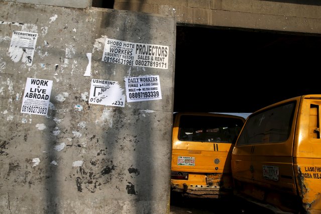 Posters advertising jobs are seen pasted on a bridge's pillar as commercial buses are seen parked in Ikeja district in Nigeria's commercial capital Lagos November 17, 2015. (Photo by Akintunde Akinleye/Reuters)