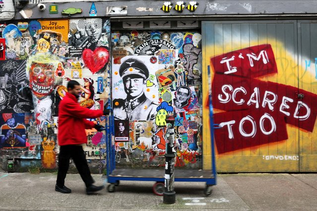 A worker walks past street art posters depicting Tesla CEO Elon Musk in World War Two Nazi German uniform, in Brick Lane, east London, Britain on March 25, 2025. (Photo by Isabel Infantes/Reuters)