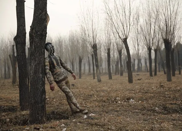 A model painted in camouflage colours to blend in with the background practises posing for Chinese artist Liu Bolin's artwork “Dongji”, or Winter Solstice, on the second day after China's capital Beijing issued its second ever “red alert” for air pollution, in Beijing, China, December 20, 2015. (Photo by Kim Kyung-Hoon/Reuters)