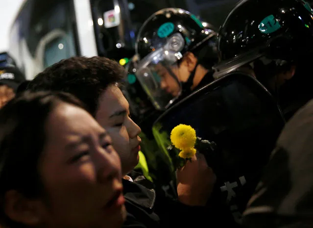 A protester holds a flower in front of riot police who block protesters on a road near the presidential Blue House during the protesters' march calling South Korean President Park Geun-hye to step down in Seoul, South Korea, November 19, 2016. (Photo by Kim Hong-Ji/Reuters)