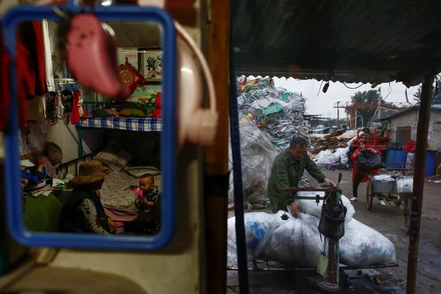 Huan (2nd R), who runs a collection stall for used textiles, receives a customer as his son Peijun sits in his hut at a recycling yard at the edge of Beijing, China, October 20, 2016. (Photo by Thomas Peter/Reuters)