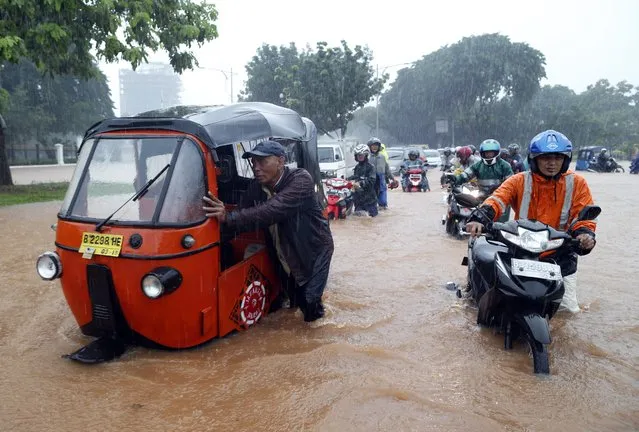 Indonesian motorists push their motorbikes as they wade through a flooded street outside the presidential palace in Jakarta, Indonesia, 09 February 2015. Incessant rain overnight  triggered widespread flooding in the Indonesian capital Jakarta, bringing traffic to a standstill. (Photo by Mast Irham/EPA)