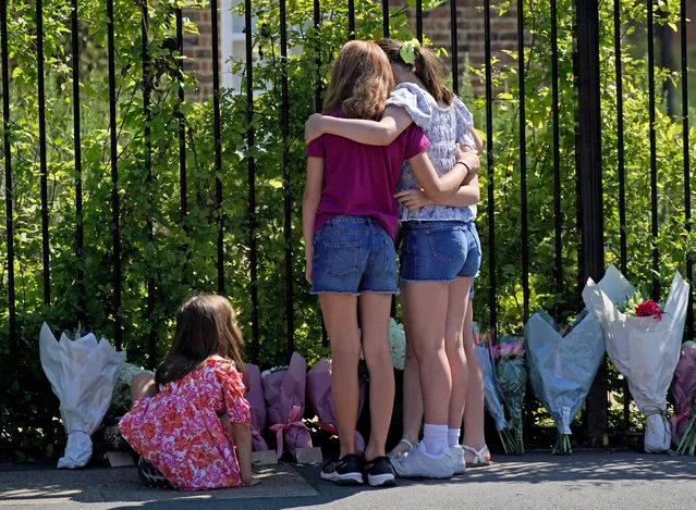 A group of children embrace as they look at the flowers and notes left outside the Study Preparatory School in Wimbledon, south-west London on Friday, July 7, 2023, after a Land Rover crashed into the girls' prep school building on the last day of term. An eight-year-old girl was killed and 10 people were taken to hospital following the incident. (Photo by Yui Mok/PA Images via Getty Images)