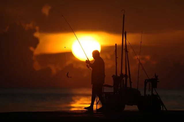 A fisherman reels in his catch as the sun rises over the Atlantic Ocean, Wednesday, June 28, 2023, in Bal Harbour, Fla. A heat dome is spreading eastward from Texas and by the weekend is expected to be centered over the mid-South, said meteorologist Bryan Jackson with the National Weather Service in College Park, Maryland. (Photo by Wilfredo Lee/AP Photo)