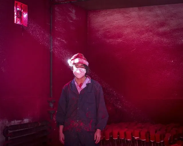 Ronghui Chen, Chinese photographer of City Express, won the Second Prize in the Contemporary Issues Category, Singles, of the 2015 World Press Photo contest with this picture of Wei, a 19-year-old Chinese worker, wearing a face mask and a Santa hat, standing next to Christmas decorations being dried in a factory as red powder used for colouring hovers in the air, in Yiwu, China, in this picture taken December 6, 2014, and released by the World Press Photo on February 12, 2015. (Photo by Ronghui Chen/Reuters/City Express/World Press Photo)