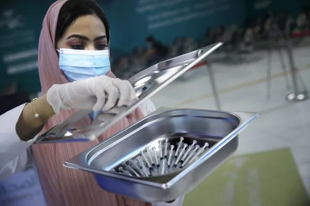 A Saudi health worker carries a tray of Pfizer coronavirus vaccines, at a vaccination center in the old Jiddah airport, Saudi Arabia, Tuesday, May 18, 2021. (Photo by Amr Nabil/AP Photo)