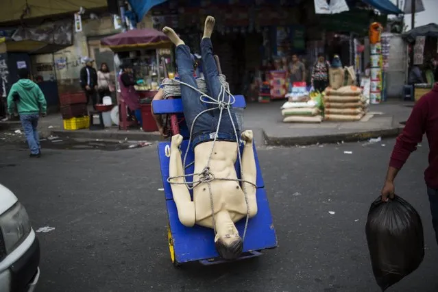 In this Monday, August 14, 2017 photo, a loader or “cargador” pulls a mannequin on his dolly at the Gamarra market, one of Latin America's largest and busiest textile markets, in Lima, Peru. Loaders are hired by vendors and shoppers to move heavy loads, and make about 60 Soles, or $18 dollars per day. (Photo by Rodrigo Abd/AP Photo)