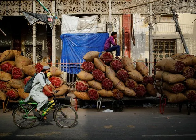 A worker sits on sacks of spices loaded on a cart at a wholesale market after authorities eased lockdown restrictions that were imposed to slow the spread of the coronavirus disease (COVID-19), in the old quarters of Delhi, India, June 8, 2021. (Photo by Adnan Abidi/Reuters)