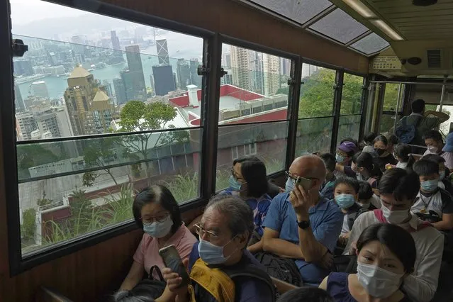 Passengers enjoy a view from the cabin as a Peak Tram goes downhill of the Victoria Peak in Hong Kong on June 17, 2021. (Photo by Vincent Yu/AP Photo)