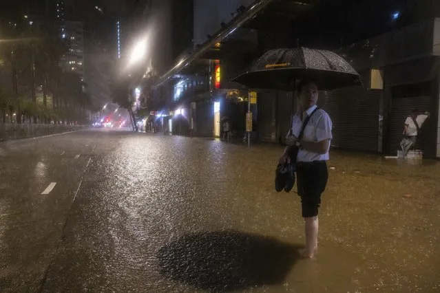 A pedestrian waits for a bus on a flooded street following heavy rainstorms in Hong Kong, Friday, September 8, 2023. (Photo by Louise Delmotte/AP Photo)