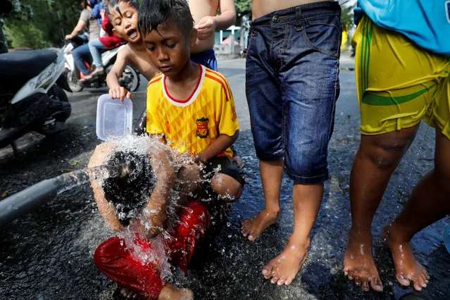 Children use a water pipe to bath at a camp for people displaced by an earthquake and tsunami in Palu, Central Sulawesi, Indonesia October 11, 2018. (Photo by Darren Whiteside/Reuters)