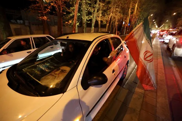 People in a car flash the “V for Victory” sign and wave an Iranian flag as they celebrate on Valiasr street in northern Tehran on April 2, 2015, after the announcement of an agreement on Iran nuclear talks. (Photo by Atta Kenare/AFP Photo)
