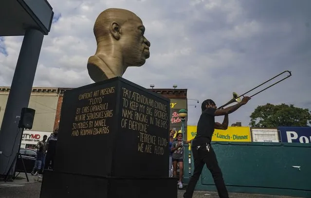 Jonte “Jonoel” Lancaster plays trombone during a celebration for the refurbished George Floyd statue, after it was vandalized following its Juneteenth installation, Thursday, July 22, 2021 in the Flatbush section of Brooklyn, N.Y. Councilwoman Farah Louis said “this culminating ceremony thank the Flatbush community for having the statue here to educate people on systemic racism” and for coming to together to restore it.  (Photo by Bebeto Matthews/AP Photo)